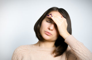 Woman with hand on forehead suffering from a headache
