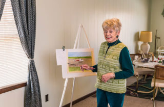 多洛丽丝·奥特，一位中风患者，在她画的OSF LIfeFlight直升机旁边摆姿势