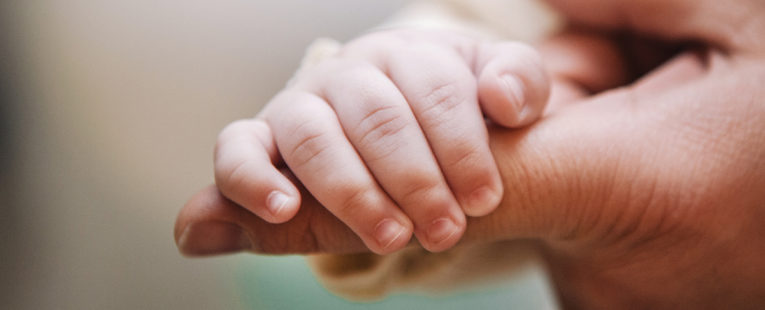 婴儿的手缠着一位先天性心脏病专家的手指