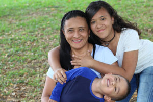 Hispanic mother with young boy with autism and teenage daughter.
