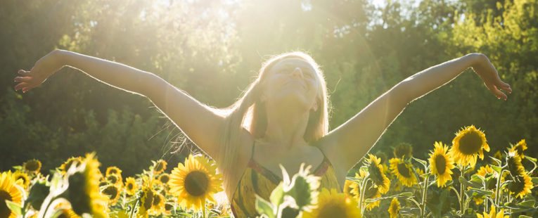 Woman stretching and relaxing in field of sunflowers