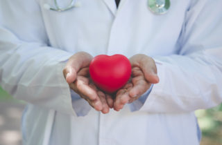 Cardiologist in white coat with toy heart.