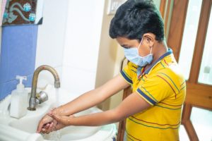 boy wearing mask washing hands