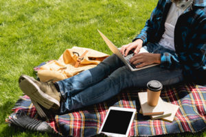 Young college student studying outdoors on a blanket.
