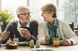male and female seniors eating healthy food smiling at each other