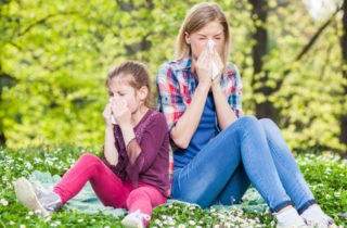 a small girl and a woman suffer with allergies outside