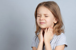 little girls holds her throat in obvious pain