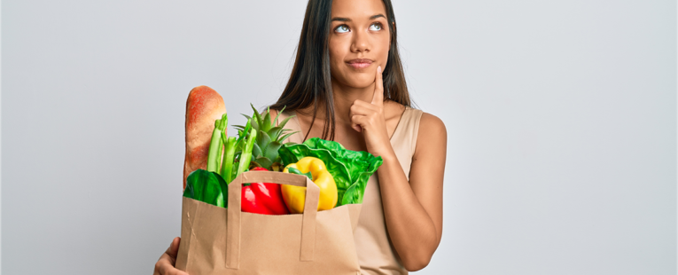 一个拎着装满健康食品的购物袋的女人看起来在思考