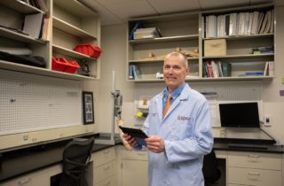 医学博士Christopher Zallek拿着一个剪贴板站在神经健康实验室里