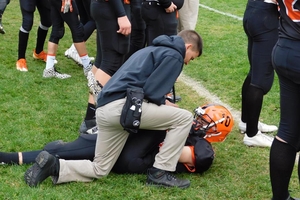 Athletic Trainer assisting a football player on a field.