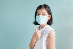 Girl with mask and band aid on arm